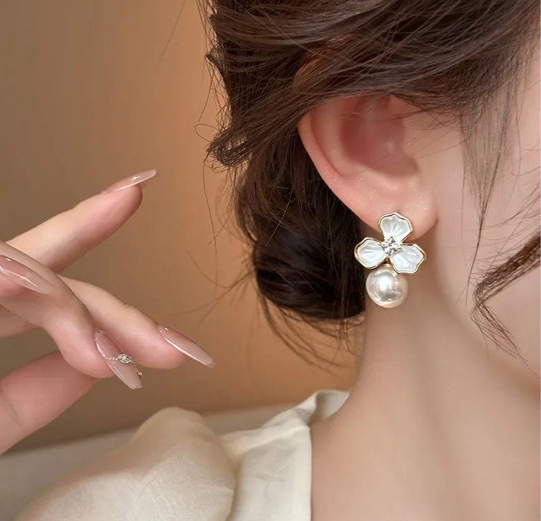 Close-up of a woman wearing a floral earring with a pearl detail.
