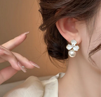 Close-up of a woman wearing a floral earring with a pearl detail.