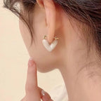 Heart-shaped earrings worn by a person with a neutral background